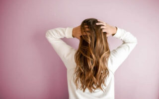A woman facing towards the wall and flaunting her gorgeous hair.