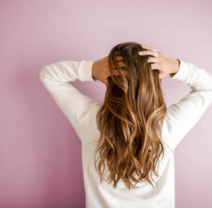 A woman facing towards the wall and flaunting her gorgeous hair.