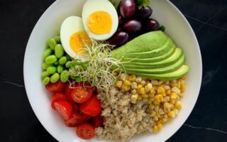 A bowl filled with high protein foods, eggs, avocados, peas, and more.