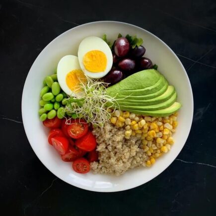 A bowl filled with high protein foods, eggs, avocados, peas, and more.