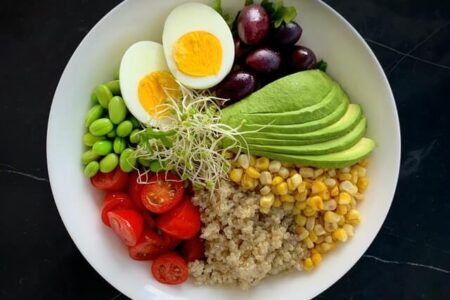 A bowl filled with high protein foods, eggs, avocados, peas, and more.