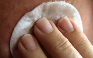 A woman cleaning a face using cotton pad during Physical Exfoliation