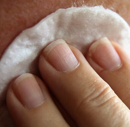 A woman cleaning a face using cotton pad during Physical Exfoliation