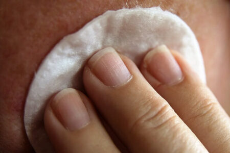 A woman cleaning a face using cotton pad during Physical Exfoliation