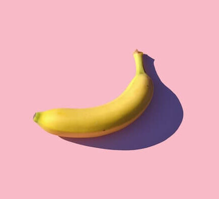 A single banana against the pink backdrop